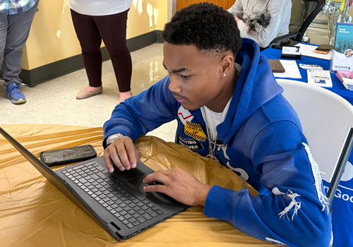 Young man learns how to apply for employment opportunities on laptop.