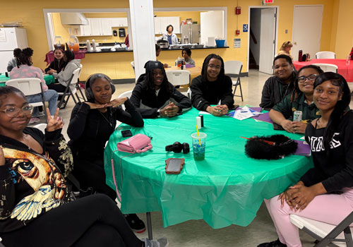 Group of young women gathered around a table enjoying time together.