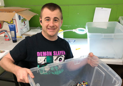 Supported Employment Smiling man sorting a big of blocks.