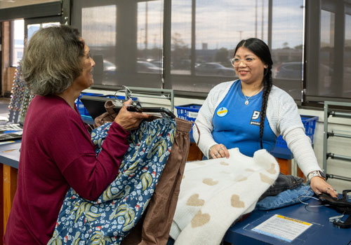Goodwill employee and volunteer sort clothing in store.